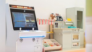 Ein Kinderspielbereich mit einer Magic Box Spielmaschine, einer Spielküchenecke und einer Spielzeugkiste.