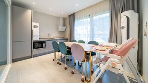 Ein modernes Hotelzimmer mit Essbereich, einer Küchenzeile und Blick auf die Stadt.