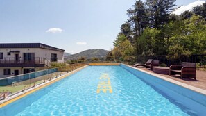Ein Schwimmbecken mit einem Schild, auf dem 'FREE' steht, umgeben von Liegestühlen und einem Gebäude mit einem Balkon.
