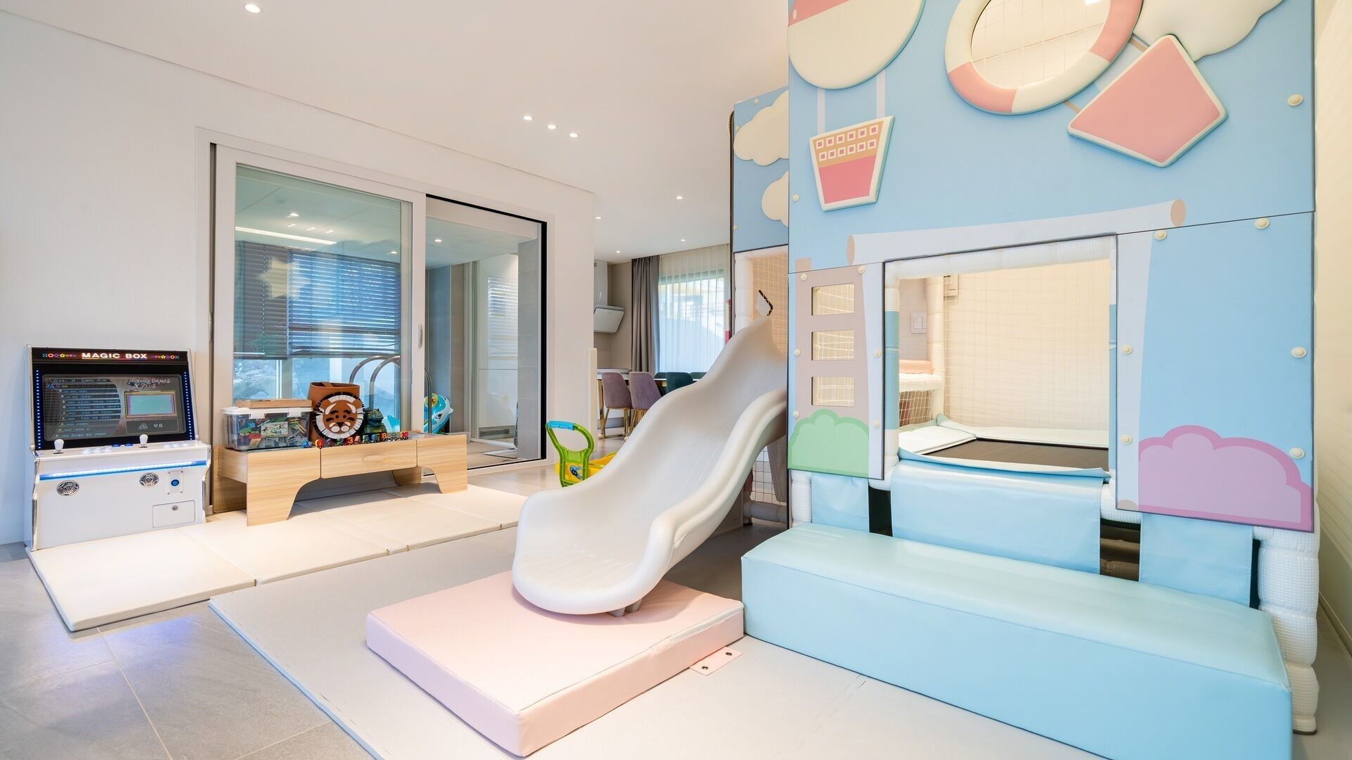 A children's play area with a slide, a play table, and a Magic Box game machine.