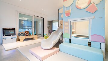A children's play area with a slide, a play table, and a Magic Box game machine.