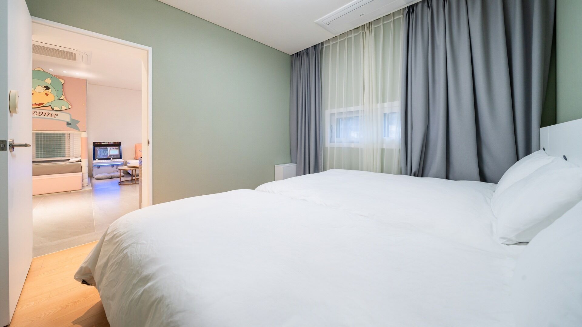 A hotel room with a large bed, a desk with a computer, and a bathroom visible through an open door.