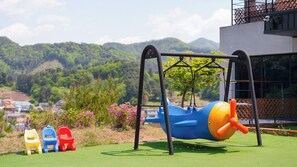 Ein Spielplatz mit Schaukeln, einer Rutsche und einer Kletterkonstruktion.