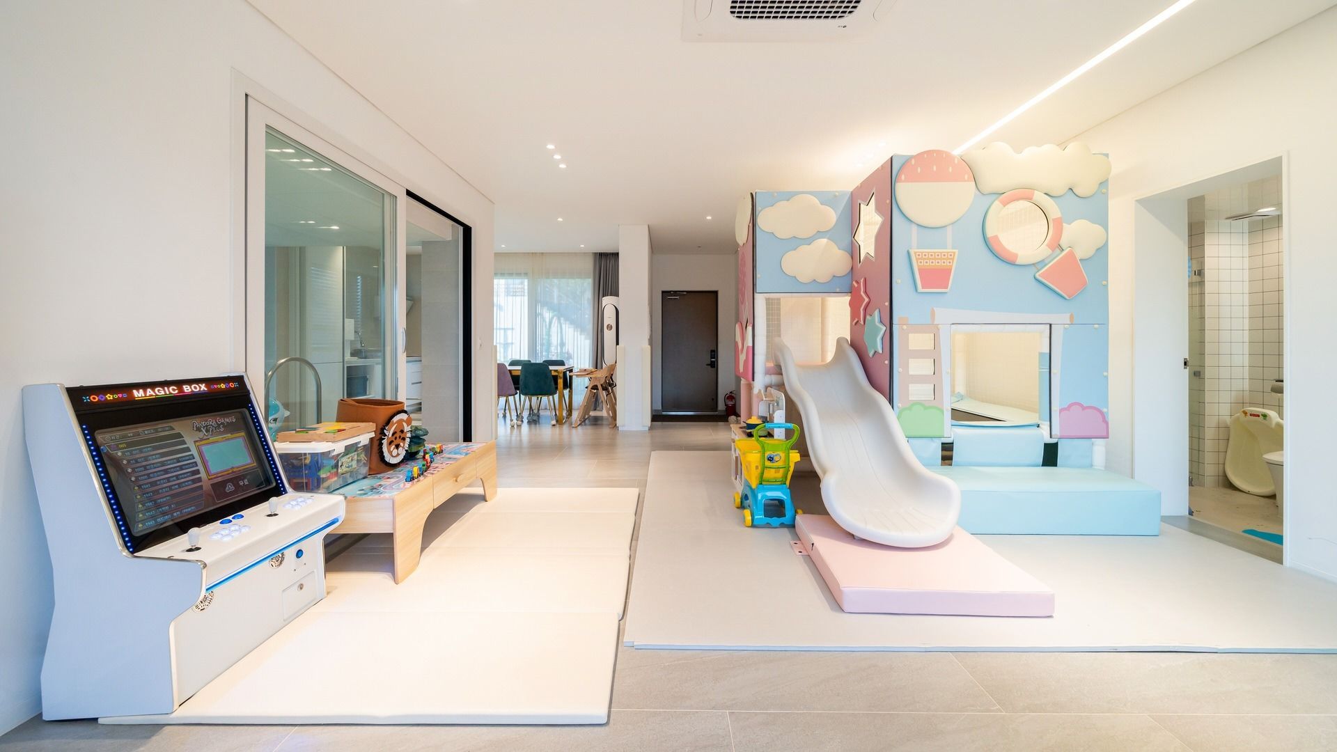 A children's play area with a slide, play mats, and a Magic Box game station.