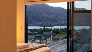 A bedroom with a large sliding glass door leading to a balcony with a mountain view.