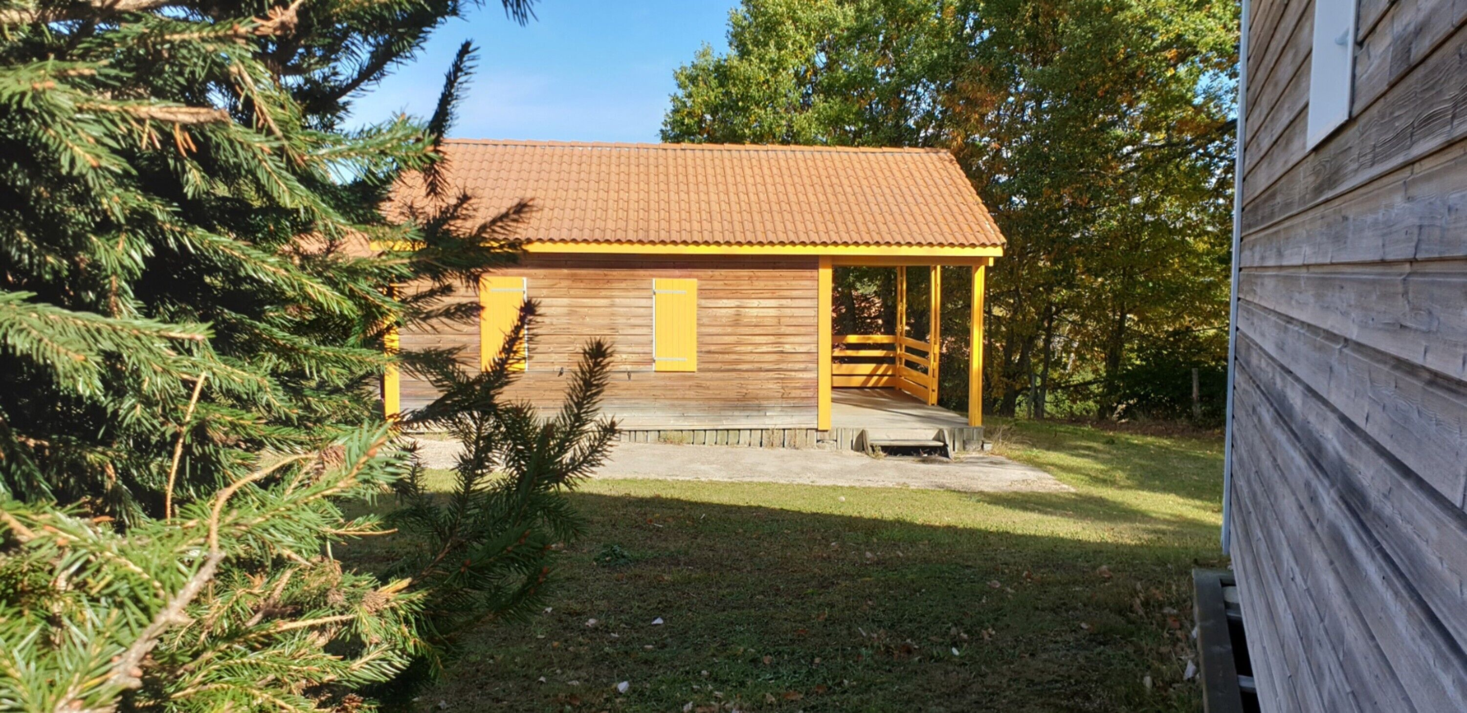 A small wooden cabin with a tiled roof, a porch, and a staircase leading to the entrance.