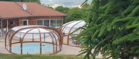 Ein Haus mit Schwimmbad, umgeben von einem Holzzaun und einer großen Nadelbaumart.