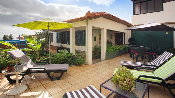 A patio with lounge chairs, a table, and a yellow umbrella.