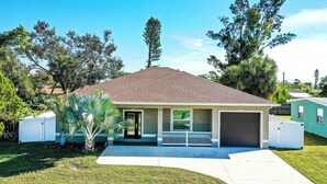 Une maison de plain-pied avec un garage, un porche à l’avant et une petite pelouse.