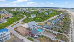 Zona residencial costera con casas, piscina y playa.