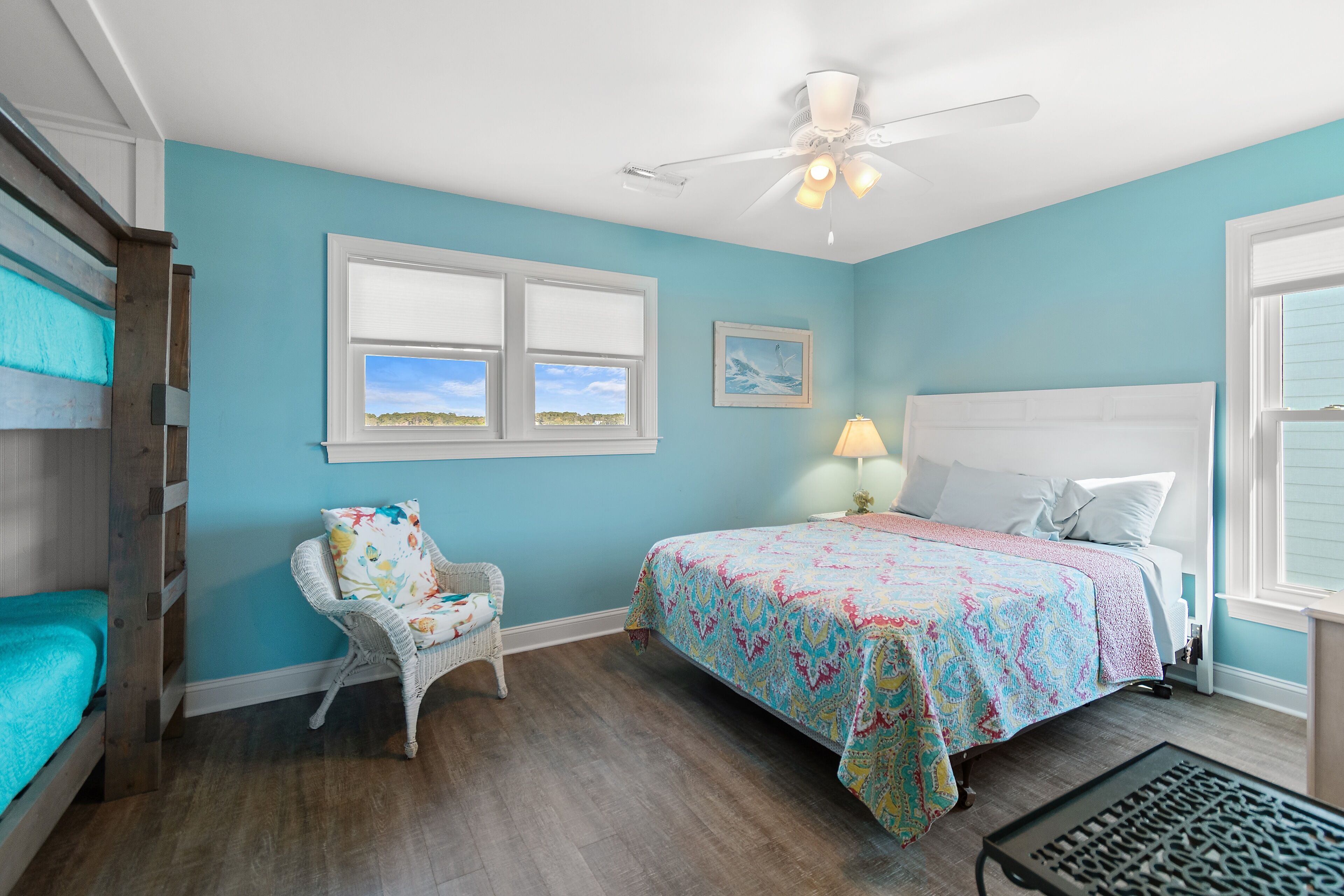 A bedroom with a bed, a chair, a ceiling fan, and a window.