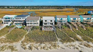 A coastal hotel with multiple buildings, a beach, and a marshy landscape.
