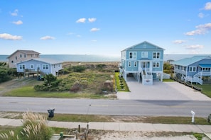 A beachfront property with multiple houses, a clear view of the ocean, and a well-maintained driveway.