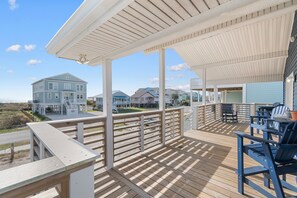 A wooden deck with outdoor seating, a covered area, and a view of houses in the background.