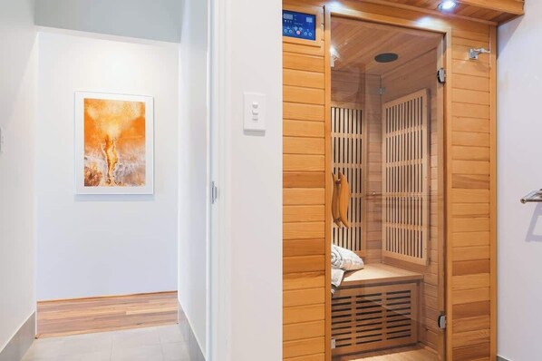 A sauna room with wooden slats, a bench, and a control panel.