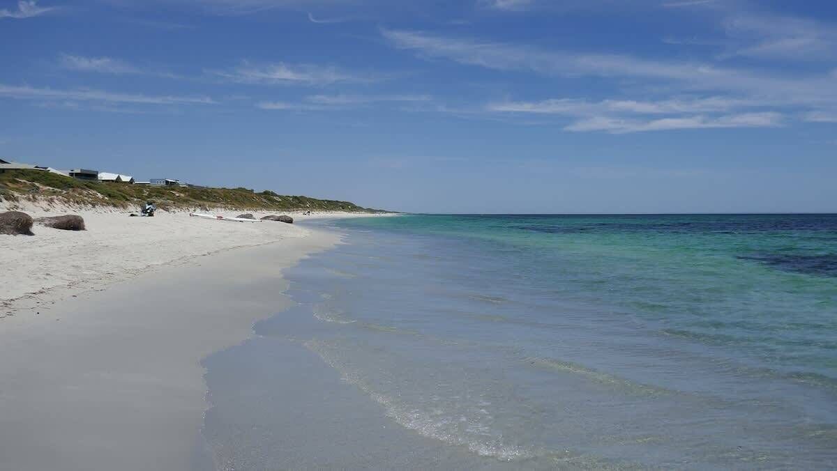 A beach with white sand and clear turquoise water.