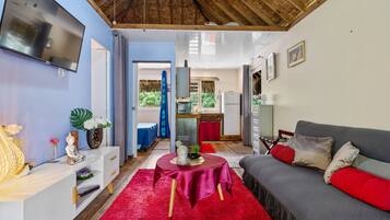 A modern living room with a grey sofa, red cushions, a red rug, and a white console table with decorative items.