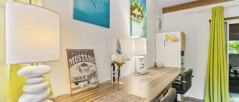 A modern kitchen with a wooden countertop, a stack of white stones, a vintage Ford Mustang poster, and a tropical-themed painting.