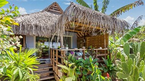 A rustic thatched-roof structure with a wooden deck, surrounded by lush tropical plants. - Fare Oaoa Haapiti (Moorea-Maiao)