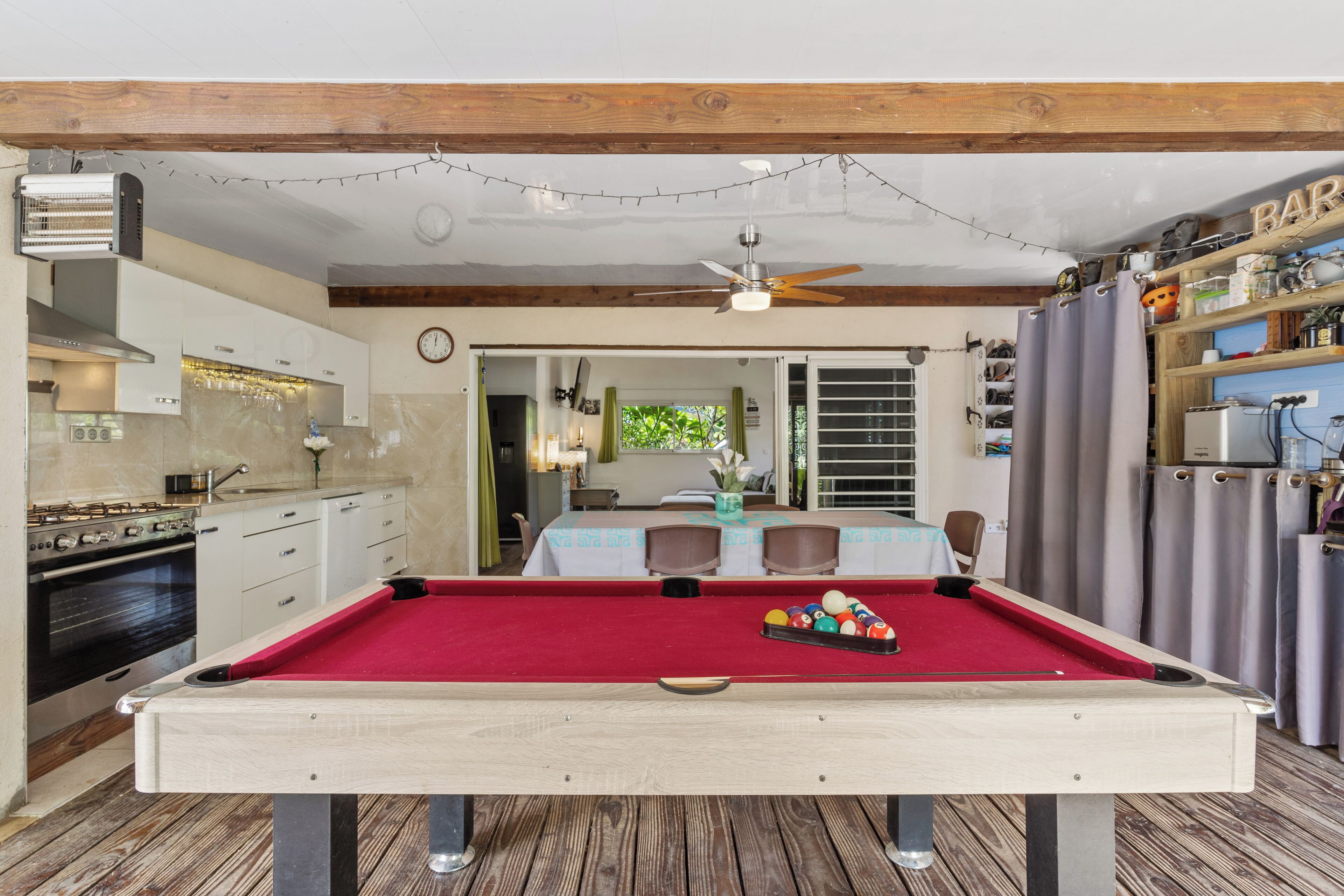 A pool table with a red felt surface, wooden pool cues, and a set of billiard balls.