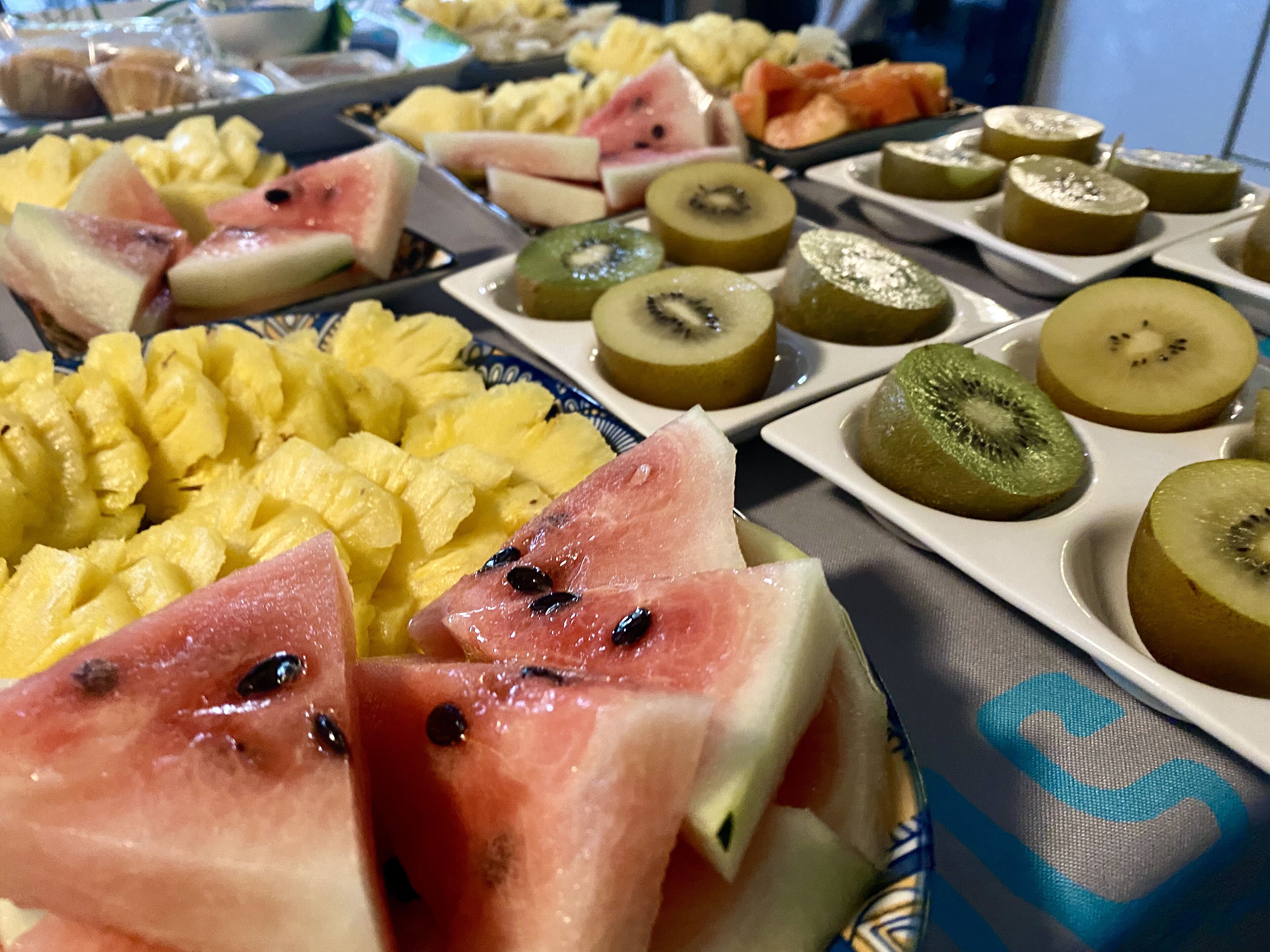 Diversas frutas como piña, sandía y kiwi dispuestas en platos.