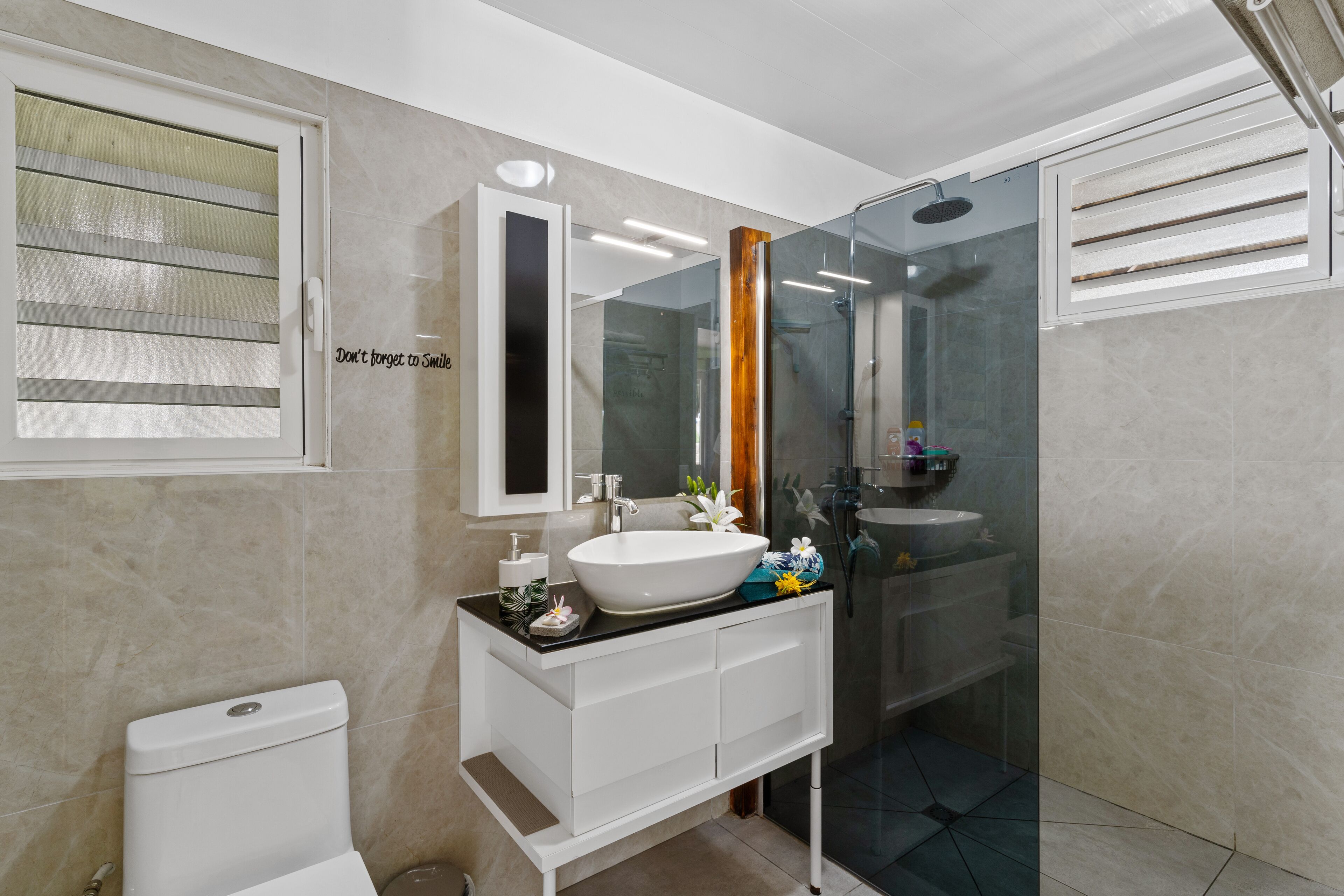 A modern bathroom with a white vanity, a large mirror, and a glass shower enclosure.