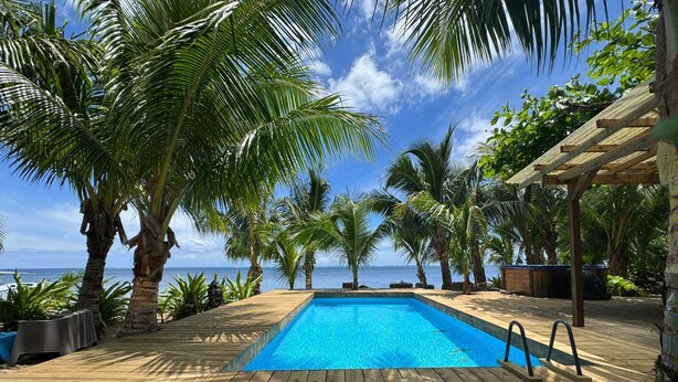 A wooden deck with a swimming pool, surrounded by palm trees and a view of the ocean. - Fare Oaoa Haapiti (Moorea-Maiao)
