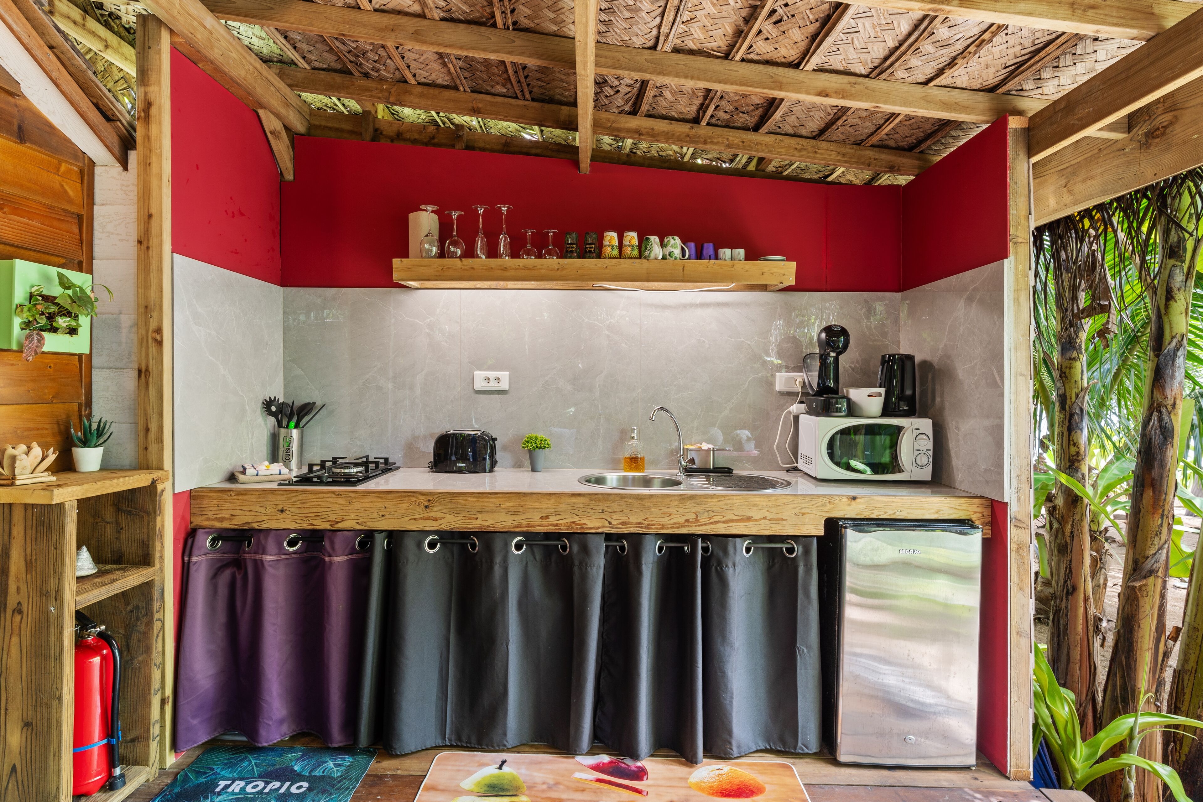 A compact kitchen with a wooden countertop, a sink, a microwave, and a refrigerator.