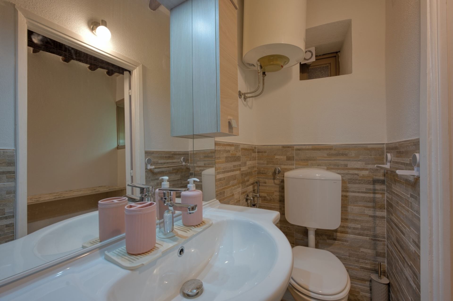 Un baño con un lavamanos blanco, un espejo, un inodoro y una zona de ducha.
