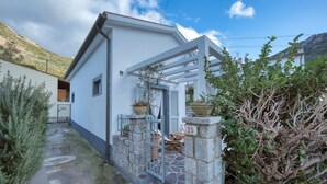 A white building with a stone entrance and a small porch area. - Casa Celeste in Pomonte (Marciana)