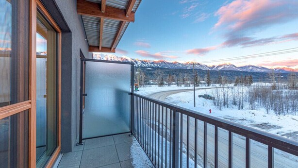 A balcony with a view of snow-covered mountains and a winding road. - Modern 2BR in Golden w/ Stunning  MTN Views! (Golden)
