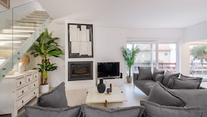 Un salon moderne avec une cheminée, un téléviseur à écran plat et un grand canapé gris.