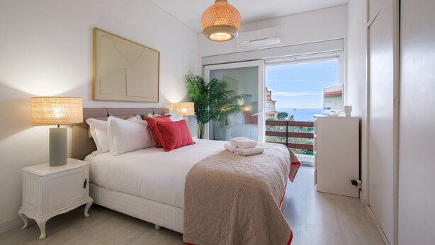 Une chambre à coucher avec un lit, des lampes de chevet, une fenêtre donnant sur un beau paysage et une plante.