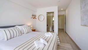 A hotel room with a bed, a bedside table with a lamp, a mirror, and a view into the bathroom. - Sea View in Estoril by Portugal Portfolio (Estoril)