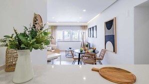 A modern dining area with a round table, wicker chairs, and a wooden cutting board. - Sea View in Estoril by Portugal Portfolio (Estoril)