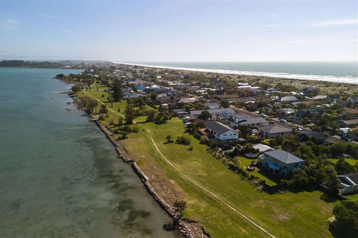 Vista aerea di una zona residenziale sulla costa, con case, un percorso ben definito lungo la spiaggia e vista sull'oceano.