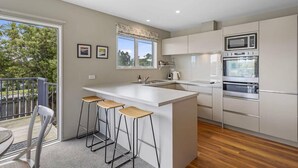 Una cocina moderna con una isla grande, taburetes de bar y vistas al exterior.