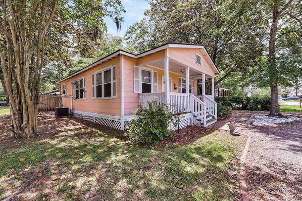 A single-story house with a porch, surrounded by trees and a grassy yard. - Park Circle's Gem | Near Downtown and Beaches (North Charleston)