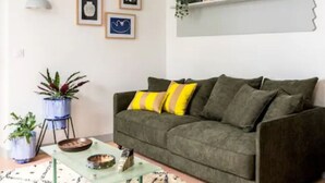 En stue med en grøn sofa, et sofabord og en potteplante.