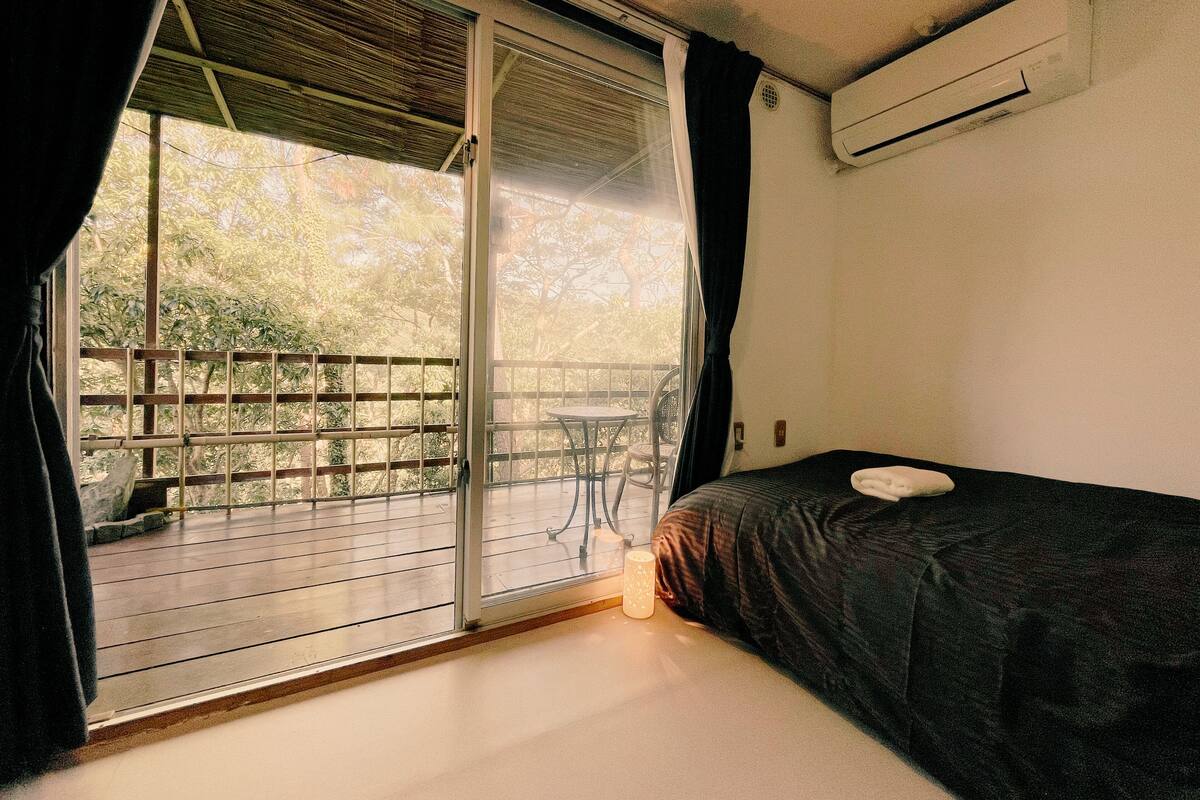 Une chambre avec un lit, une table et une vue sur un balcon doté d’une balustrade.