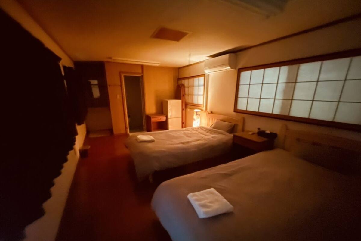 Une chambre d’hôtel avec deux lits, une table de chevet, une lampe et une fenêtre donnant sur un beau paysage.