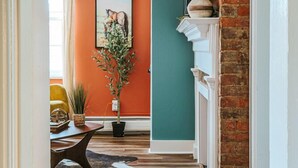 Un couloir avec un plancher en bois, une plante en pot, un tableau encadré et un mur en briques.
