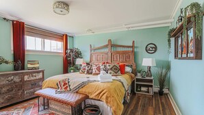 Une chambre confortable avec un lit en bois, un banc, une commode et une fenêtre avec des rideaux.