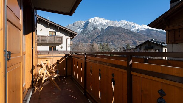 Un balcone in legno con vista sulle montagne innevate.