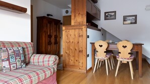 Un accogliente soggiorno con un divano a quadri, un tavolo da pranzo in legno con sedie a forma di cuore e un armadio in legno.