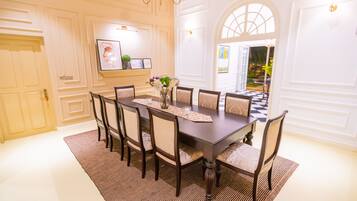 A formal dining room with a dark wooden table, eight upholstered chairs, a patterned runner, and a chandelier.