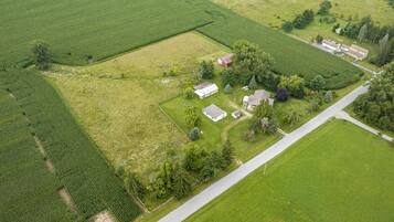 An aerial view of a rural property with fields, a road, and several buildings.