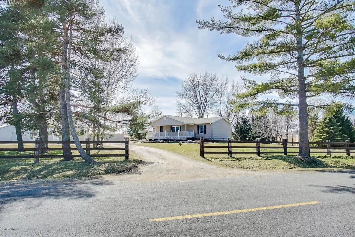 A single-story house with a porch, surrounded by a wooden fence and trees.