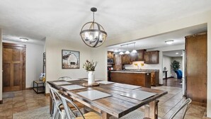 A spacious kitchen with wooden cabinets, a central island, and a hanging light fixture.
