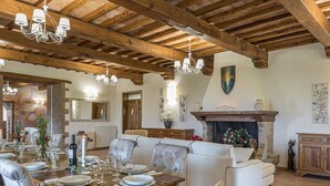 A dining area with a wooden table set for a meal, surrounded by upholstered chairs. - Tenuta Montiepoli 12 3 Emma Villas (Valfabbrica)
